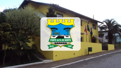 Fachada da prefeitura de Ponte Alta do Norte, prédio amarelo com bandeiras e o brasão do município em destaque no centro da imagem.