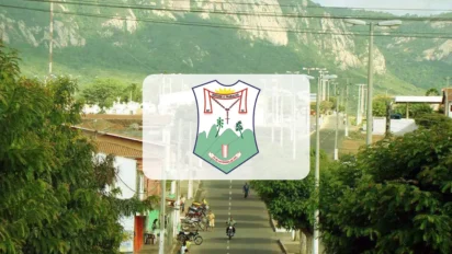 Vista aérea de uma rua em Monsenhor Tabosa com o brasão do município centralizado em um quadro branco sobreposto à imagem que mostra montanhas ao fundo e vegetação urbana.