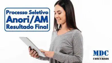 Mulher sorridente de cabelo liso e escuro usando uma blusa cinza enquanto segura e interage com um tablet em um fundo branco - Prefeitura de Anori (AM) homologa Resultado Final do Processo Seletivo 0032025