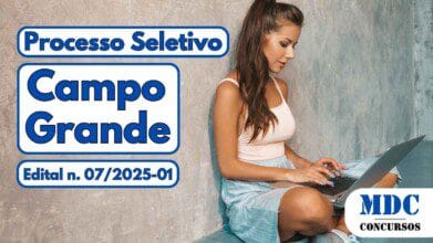 Mulher jovem sentada no chão, encostada em parede cinza texturizada, usando top branco e saia azul clara, digitando em um laptop prateado - Prefeitura de Campo Grande oferece 226 Vagas em novo Processo Seletivo