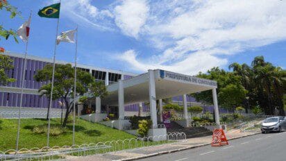 Fachada da Prefeitura de Contagem/MG com bandeiras hasteadas, prédio moderno de cor roxa e área ajardinada em dia ensolarado. Foto: Divulgação/Câmara de Contagem-MG