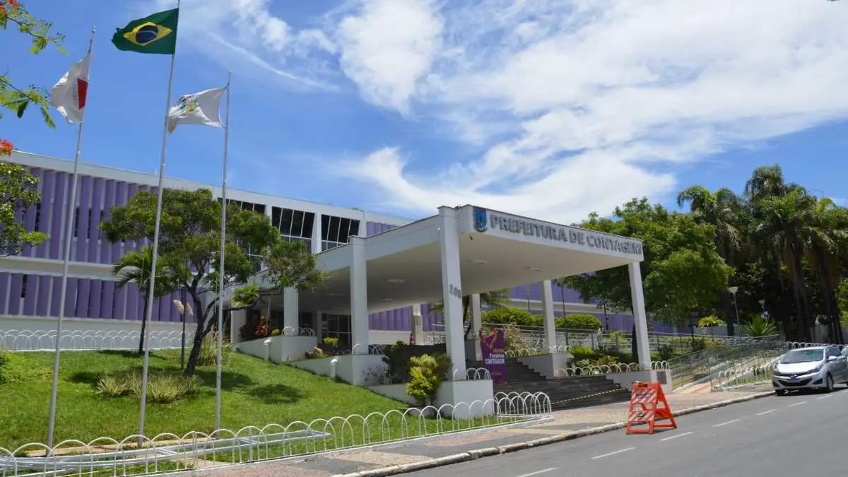 Fachada da Prefeitura de Contagem/MG com bandeiras hasteadas, prédio moderno de cor roxa e área ajardinada em dia ensolarado. Foto: Divulgação/Câmara de Contagem-MG
