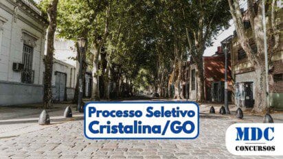 Rua de paralelepípedos arborizada com árvores altas formando um túnel verde, ladeada por prédios baixos residenciais e comerciais - Prefeitura de Cristalina (GO) oferece 320 vagas em Processo Seletivo