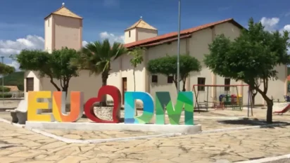 Letreiro colorido “EU ❤️ DM” em praça pública de Domingos Mourão, com árvores, playground e igreja ao fundo, em um cenário urbano sob céu azul. Foto: Divulgação/Prefeitura de Domingos Mourão-PI