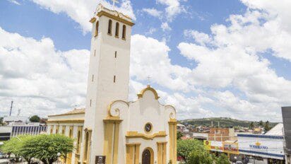 Igreja Matriz de Sant’Ana em Gravatá-PE com torre alta, fachada branca e detalhes em amarelo, sob céu azul com nuvens. Foto: Bruno Lima - MTUR/Wikipédia