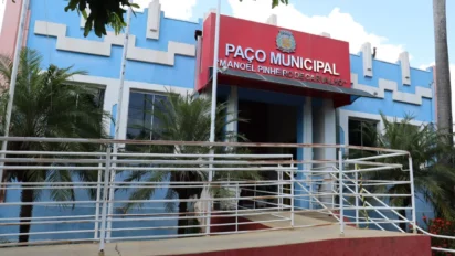 Fachada do Paço Municipal de Indiana, São Paulo, um prédio azul e branco com detalhes arquitetônicos geométricos, rampa de acessibilidade e letreiro vermelho com o nome do local.