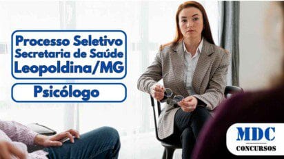 Mulher com expressão séria segura óculos durante uma conversa em grupo, sentada em uma sala iluminada com luz natural - Prefeitura de Leopoldina (MG) abre vaga de Psicólogo com remuneração de R$3,9 mil em Processo Seletivo