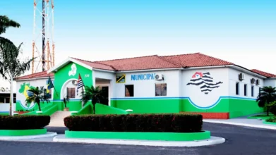 Concursos 6 Fachada da Prefeitura Municipal de Macaubal, um prédio térreo nas cores branca e verde, com telhado de barro e o mapa do estado de São Paulo pintado na parede.