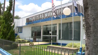 Fachada frontal do prédio da Prefeitura Municipal de Martinópolis, com paredes brancas, detalhes em azul, rampa de acessibilidade e bandeiras hasteadas à frente.