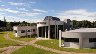 Processos Seletivos 4 Prédio moderno da Prefeitura Municipal de Nova Mutum com fachada envidraçada, bandeiras hasteadas e gramado ao redor. Foto: Divulgação/Prefeitura de Nova Mutum-MT