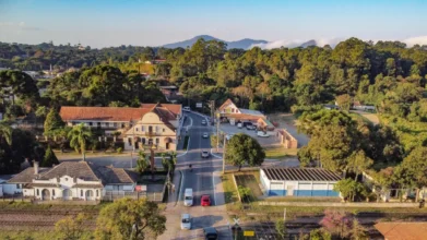 Vista aérea de área urbana de Piraquara com casas, avenida principal, linha férrea e vegetação ao redor. Foto: Divulgação/Prefeitura de Piraquara-PR