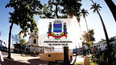 Vista de uma praça ensolarada em Porto Feliz com árvores, bancos e uma igreja ao fundo. Centralizado, o brasão da cidade sobrepõe a imagem com o texto Prefeitura Municipal de Porto Feliz.
