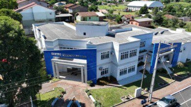 Processos Seletivos 2 Vista aérea do prédio do Centro Administrativo e da Câmara de Vereadores de Princesa SC, com fachada branca e detalhes em azul.
