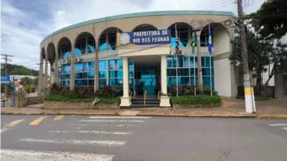 Fachada da Prefeitura de Rio das Pedras com prédio de dois andares, arcos na parte superior, vidros azuis e bandeiras hasteadas na entrada. Foto: Divulgação/Prefeitura de Rio das Pedras-SP