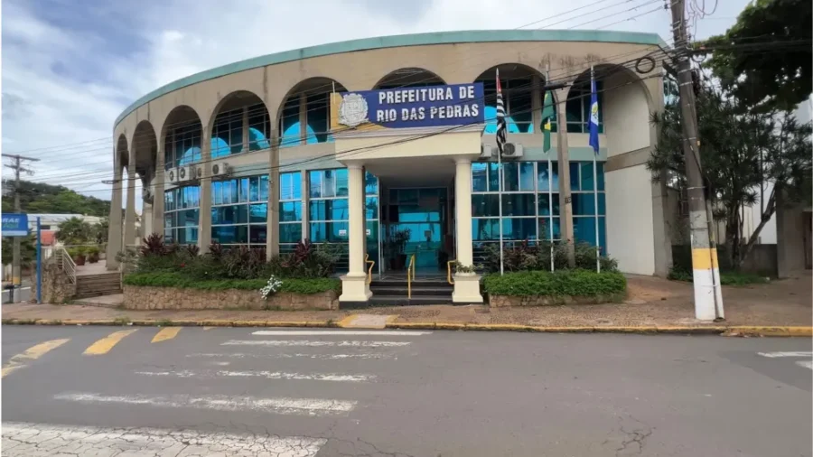 Fachada da Prefeitura de Rio das Pedras com prédio de dois andares, arcos na parte superior, vidros azuis e bandeiras hasteadas na entrada. Foto: Divulgação/Prefeitura de Rio das Pedras-SP