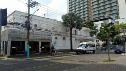 Fachada da Central de Operação e Controle da Prefeitura de Três Rios, com pessoas na calçada e uma van oficial estacionada em frente.