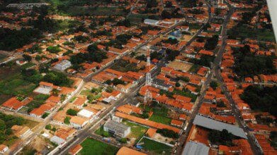 Processos Seletivos 3 Vista aérea da cidade de União, no estado do Piauí, com casas de telhado vermelho, ruas pavimentadas, áreas verdes e uma torre de telecomunicação ao centro.
