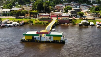 Prefeitura de Urucará/AM abre processo seletivo com 555 vagas 2 Vista aérea do porto flutuante de Urucará com balsa nas cores verde e amarela e letreiro de boas-vindas, conectada à orla da cidade por uma rampa. Foto: Divulgação/Mauro Neto/Secom - Governo do Amazonas