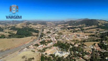 Vista aérea da cidade de Vargem, com áreas urbanas, estrada principal, morros ao redor e o logotipo da Prefeitura de Vargem no canto superior esquerdo. Foto: Divulgação/Prefeitura de Vargem-SP