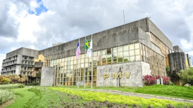 Fachada do edifício da Prefeitura Municipal de Vitória (PMV), com jardins em primeiro plano, bandeiras hasteadas e céu nublado ao fundo. Foto: Divulgação/Prefeitura de Vitória