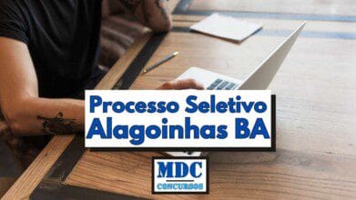 Processos Seletivos 9 Homem tatuado utiliza notebook sobre uma mesa de madeira enquanto ao fundo há um caderno e uma caneta, com destaque para um banner central com os dizeres Processo Seletivo Alagoinhas BA em letras azuis e a logomarca MDC Concursos abaixo do texto, representando uma chamada visual para divulgação de oportunidades de emprego na área social em Alagoinhas na Bahia