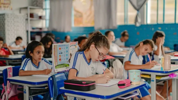 Processo Seletivo Anápolis GO: SEMED adia Resultado Final; veja mudanças 5 Alunos uniformizados escrevem em sala de aula ilustrando processo seletivo Anápolis GO