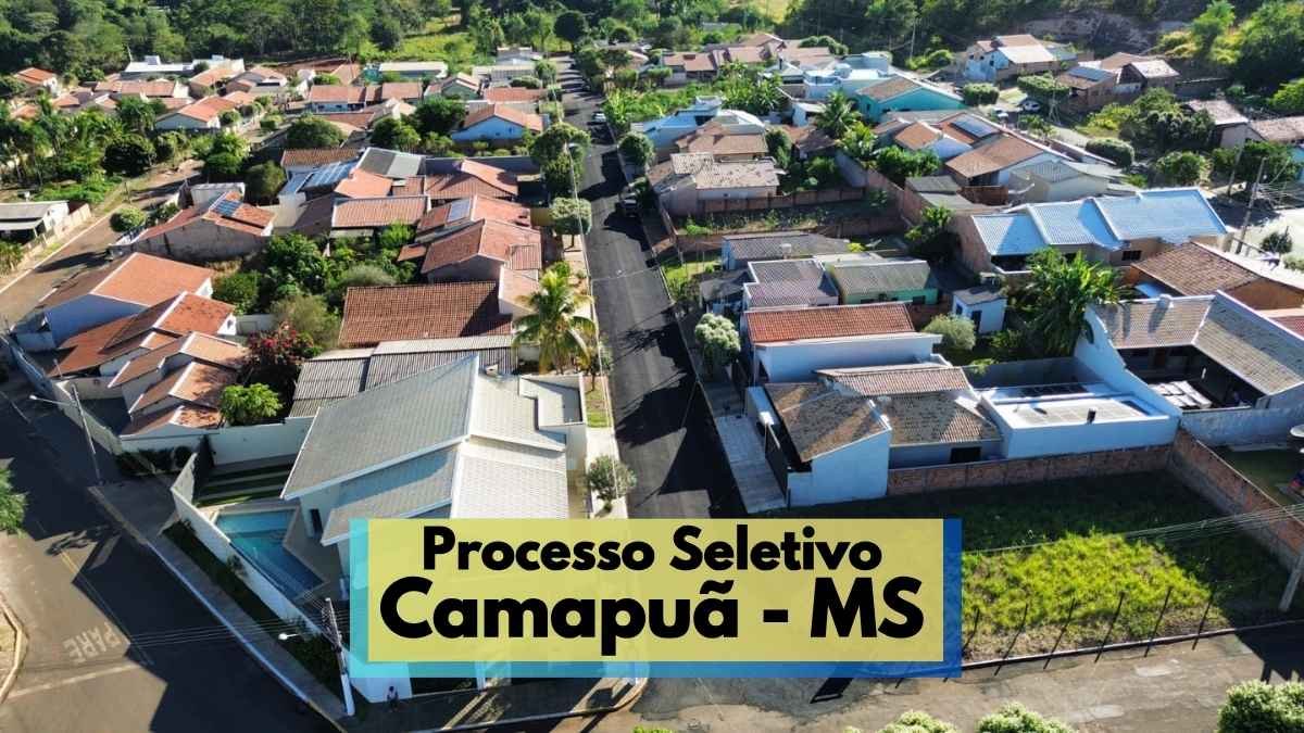 Processo Seletivo Camapuã MS tem salários de até R$ 7,7 mil 1 Imagem aérea de um bairro residencial em Camapuã, no Mato Grosso do Sul, mostrando ruas asfaltadas e casas com telhados variados cercadas por vegetação. Ao centro, destaca-se uma rua principal alinhada com árvores. No canto inferior, há uma faixa com os dizeres “Processo Seletivo Camapuã - MS”, indicando a realização de um processo seletivo na cidade, com destaque visual chamativo.