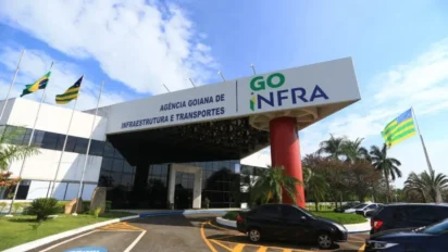 Fachada da Agência Goiana de Infraestrutura e Transportes (GOINFRA) com letreiro e bandeiras do Brasil e de Goiás hasteadas em frente ao prédio. Foto: Divulgação/GOINFRA
