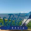 Totem turístico com o nome Porto Seguro Bahia ao fundo do mar, cenário do processo seletivo REDA Porto Seguro BA