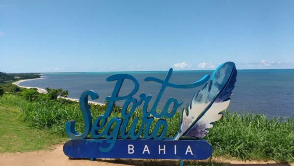 Totem turístico com o nome Porto Seguro Bahia ao fundo do mar, cenário do processo seletivo REDA Porto Seguro BA