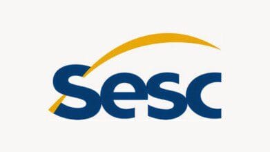Processos Seletivos 9 Logotipo do SESC com a palavra "Sesc" escrita em letras minúsculas, grossas e arredondadas na cor azul escuro, com uma curva amarela estilizada que começa no canto inferior esquerdo e se estende sobre as letras até o canto superior direito, formando um arco que remete a movimento e dinamismo, sobre fundo branco claro e aparência moderna e institucional - SESC ES