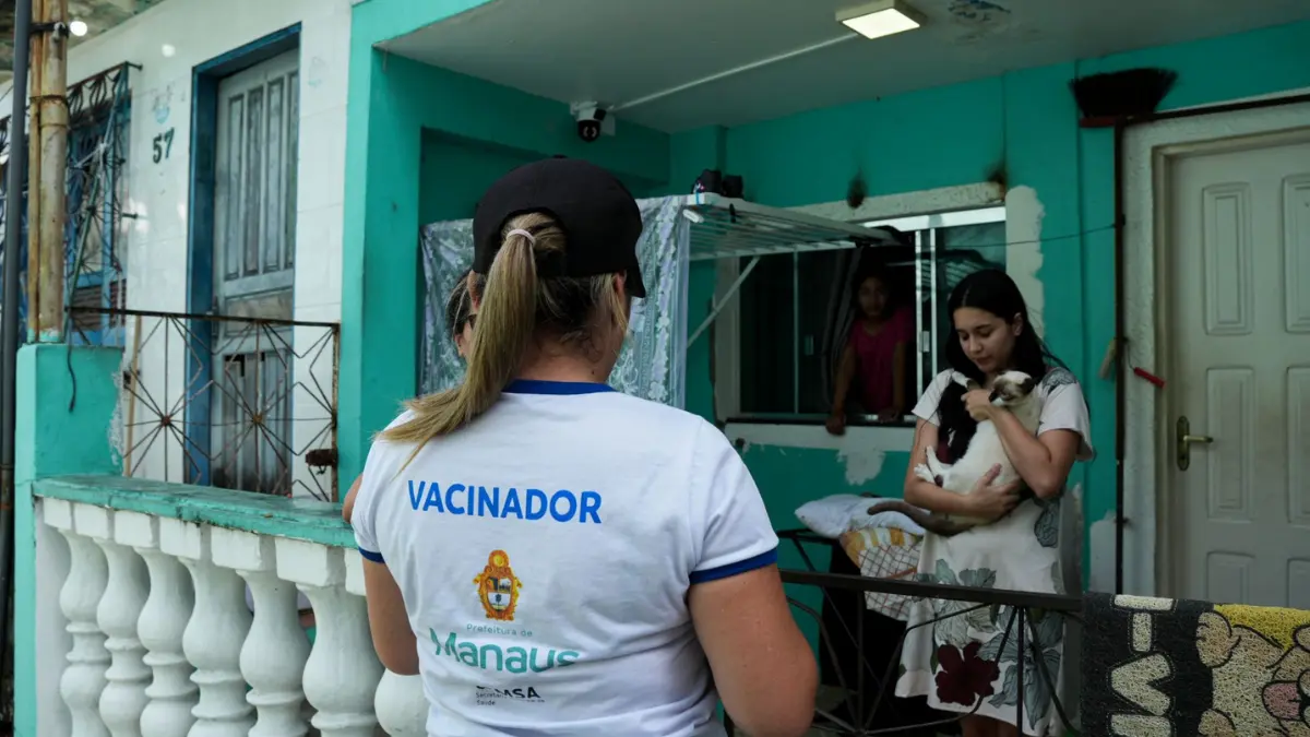 Processo Seletivo Semsa Manaus abre 295 vagas com salários de até R$ 8.764,38 1 Vacinadora com camiseta da Prefeitura de Manaus atende moradora no processo seletivo Semsa Manaus