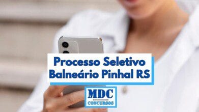Imagem de uma pessoa segurando um smartphone prateado com duas câmeras traseiras, enquanto usa uma camisa branca, parcialmente visível e desfocada ao fundo. Sobre a imagem, há um retângulo branco com bordas azuis contendo o texto em destaque “Processo Seletivo Balneário Pinhal RS”. Abaixo, há o logotipo da MDC Concursos em azul com letras grandes e destaque para a palavra MDC