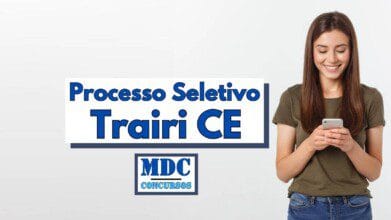 Processos Seletivos 5 Imagem com fundo claro mostrando uma jovem sorridente de cabelos longos castanhos, vestindo camiseta verde-oliva e jeans, olhando para o celular nas mãos. Ao lado esquerdo da imagem está o texto “Processo Seletivo Trairi CE” em letras grandes azul-escuro com sombra, e abaixo o logotipo da MDC Concursos, indicando a divulgação de um novo processo seletivo na cidade de Trairi no Ceará