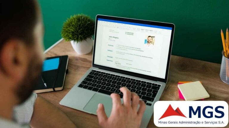 Homem visualiza um currículo digital em um notebook, com destaque para dados pessoais, resumo profissional e foto de perfil de um candidato chamado John Rogers. A cena se passa em um ambiente de trabalho organizado, com caderno, caneta, bloco de notas colorido, porta-lápis e um pequeno vaso decorativo sobre a mesa de madeira. No canto inferior direito, aparece o logotipo da MGS (Minas Gerais Administração e Serviços S.A.).
