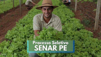 Homem com chapéu de palha e camisa bege sorri enquanto segura uma alface fresca em uma plantação organizada de hortaliças, com solo avermelhado. Ao fundo, outras pessoas trabalham entre as fileiras de pés de alface. A imagem ilustra o ambiente rural e o trabalho agrícola, com destaque para o texto “Processo Seletivo SENAR PE” sobreposto na parte inferior da foto.