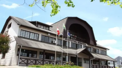 Sede da Prefeitura Municipal de Rio Negrinho com fachada em estilo germânico, bandeiras hasteadas, janelas amplas e entrada central sob estrutura arqueada. Foto: Divulgação/Prefeitura de Rio Negrinho-SC