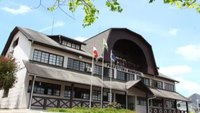 Sede da Prefeitura Municipal de Rio Negrinho com fachada em estilo germânico, bandeiras hasteadas, janelas amplas e entrada central sob estrutura arqueada. Foto: Divulgação/Prefeitura de Rio Negrinho-SC