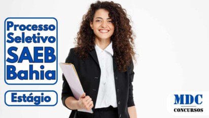 Mulher jovem de cabelos cacheados vestindo terno preto e camisa branca, sorrindo e segurando uma pasta branca contra um fundo branco - SAEB Bahia oferece 100 Vagas em Programa de Estágio de Pós-Graduação