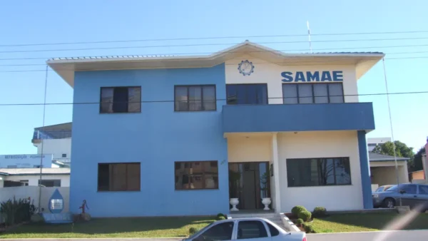 Fachada da sede do SAMAE em Campos Novos, um prédio de dois andares nas cores azul e bege, com o logotipo e o nome da autarquia em destaque na parte superior. Foto: Deyvid Setti e Eloy Olindo Setti/Wikipédia