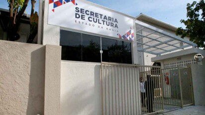 Fachada da Secretaria de Cultura do Estado da Bahia com portão metálico e placa de identificação na entrada.