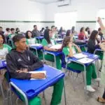 Professora ministra aula para turma de estudantes uniformizados em sala com carteiras azuis e paredes revestidas de azulejos brancos. Foto: Divulgação/SEDUC-PI