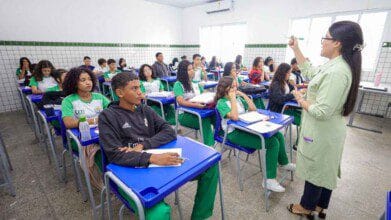 Professora ministra aula para turma de estudantes uniformizados em sala com carteiras azuis e paredes revestidas de azulejos brancos. Foto: Divulgação/SEDUC-PI