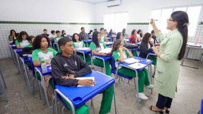 Professora ministra aula para turma de estudantes uniformizados em sala com carteiras azuis e paredes revestidas de azulejos brancos. Foto: Divulgação/SEDUC-PI