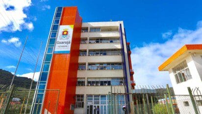 Fachada do Paço Municipal de Guarujá/SP com prédio de vários andares, estrutura colorida em laranja e azul e céu azul ao fundo. Foto: Divulgação/Prefeitura de Guarujá-SP