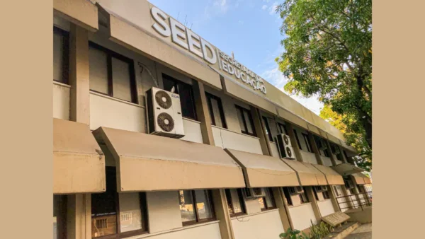 SEED Amapá abre concurso com 404 vagas e salários de até R$ 6.600,98 3 Fachada de um prédio bege de dois andares com a inscrição SEED Secretaria da Educação em destaque no topo. O edifício possui janelas escuras, aparelhos de ar-condicionado externos e coberturas metálicas inclinadas sobre as janelas do térreo. Uma árvore aparece à direita sob céu claro. Foto: Divulgação/SEED-AP