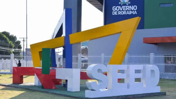 Escultura com letras coloridas formando a sigla SEED em frente a prédio do Governo de Roraima, com placa institucional ao fundo. Foto: Divulgação/Governo de Roraima