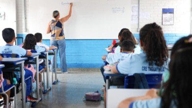 Processos Seletivos 2 Professora escreve no quadro em sala de aula enquanto alunos uniformizados acompanham sentados em carteiras. Foto: Divulgação/Felipe de Noronha/SEEDF