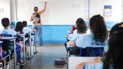 Professora escreve no quadro em sala de aula enquanto alunos uniformizados acompanham sentados em carteiras. Foto: Divulgação/Felipe de Noronha/SEEDF