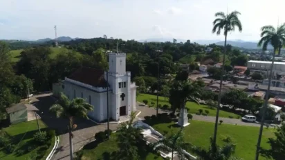 Vista aérea da Igreja Matriz de Nossa Senhora da Lapa, em Silva Jardim-RJ, cercada por área verde e com parte da cidade e colinas ao fundo. Foto: Divulgação/Prefeitura de Silva Jardim-RJ